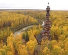 Muž staví v divokých lesích věž z domů