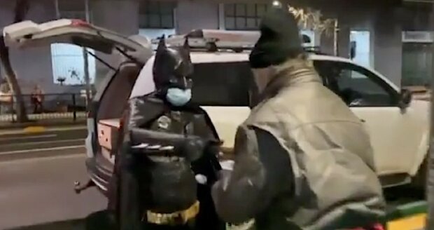 Muž v kostýmu Betmana rozdává jídlo bezdomovcům